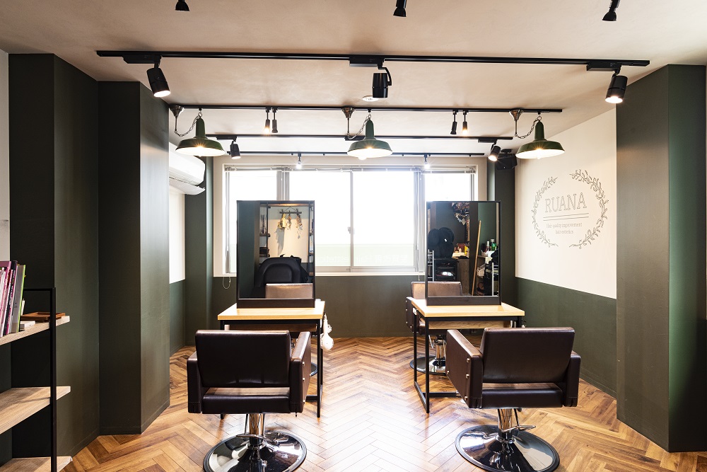 AInoa RUANA 青山の店内。木の床と落ち着いたグリーンの壁、セット面